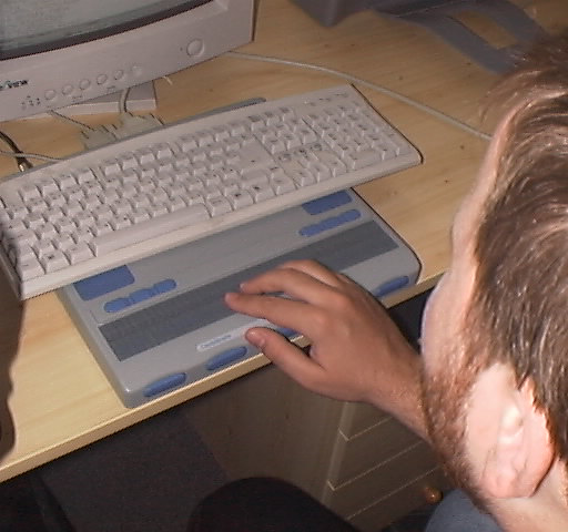 Utente al computaer con display Braille